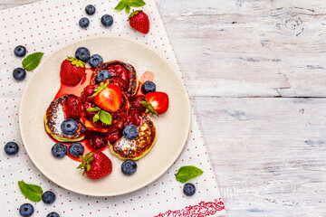 Cottage cheese pancakes with fresh berries and strawberry sauce. Healthy breakfast concept on wooden background