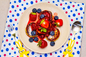 Cottage cheese pancakes with fresh berries and strawberry sauce. Healthy breakfast concept for kids on stone background