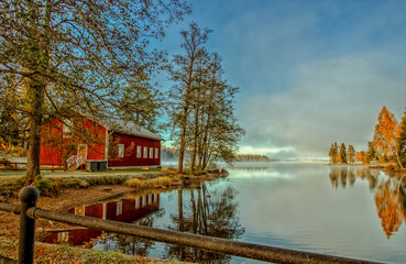 Fototapeta na wymiar Sweden / Filipstad, foggy morning at the lake with a typical red Swedish house