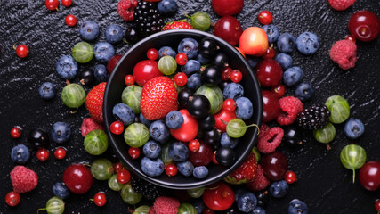 Collection of wild berries on black background, top view