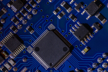 Close-up of a blue printed circuit board (PCB) with stripes of conductors between a transistor and...