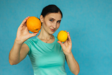 A young girl is holding an orange and a lemon. Tropical fruit. Girl on a blue background.