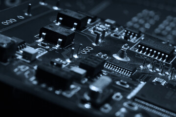 Fototapeta na wymiar Fragment and components of a motherboard (PCB) of computer technology with many elements. Macro photography of processors and transistors. IT industry background