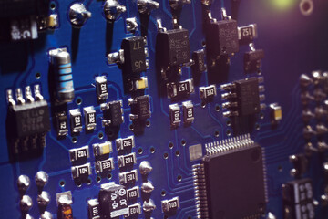 Close-up of a blue printed circuit board (PCB) with stripes of conductors between a transistor and...