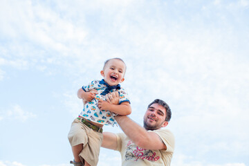 Father having fun with son against blue sky