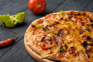Vegetarian hot chili pizza on a wooden Board among vegetables and hot peppers, close-up