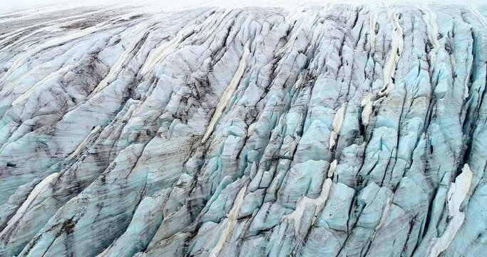 Slow aerial drone ride over the glacier, revealing high details of natural ice and rocks and his relief surrounded by fog. Natural landscape in 4K