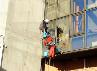 Limpiacristales trabajando en un edificio de oficinas. Trabajos en vertical