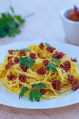 spaghetti with sun-dried red tomatoes and parsley on wooden background