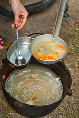 Fish soup is cooked on the fire. Ears in an iron bowl in nature.