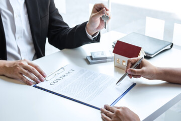 Estate agent giving house keys to client after signing agreement contract