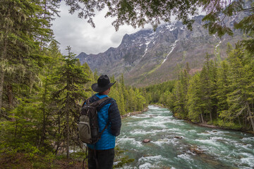 Hiker looking out over McDonald Creek and mountain background
