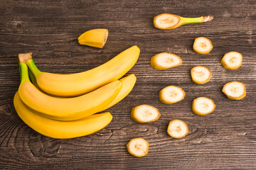 Bunch of raw organic yellow bananas with slices on wooden background - 369314161