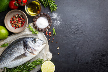 Fresh ready to cook raw bream fish dorado with ingredients and seasonings like rosemary, salt, pepper, lime and olive oil, top view