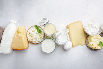 Fresh dairy products, milk, cottage cheese, eggs, yogurt, sour cream and butter on white table, top...