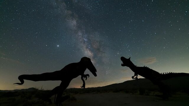Time lapse tracking shot of Milky Way galaxy over roaring dinosaurs in Anza Borrego Desert in California