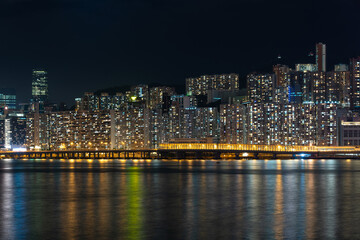Fototapeta na wymiar Hong Kong cityscape at night over Victoria Harbor with clear sky and urban skyscrapers.