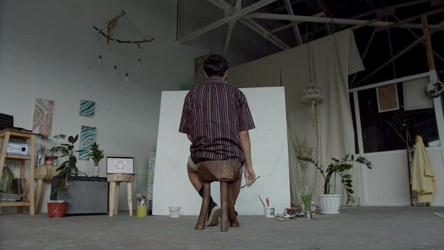 male artist begins his artwork on big white canvas