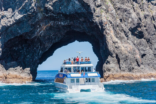 Tour boat entering The Hole in the Rock in Bay of Islands, New Zealand