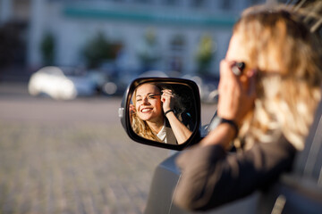 Beautiful young woman with blond curly hair wearing a suit  and glasses with pistol in a car...