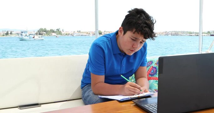 Teenage boy studying on yacht deck Online learning education distance learning for kids at home Homeschooling during quarantine or isolation