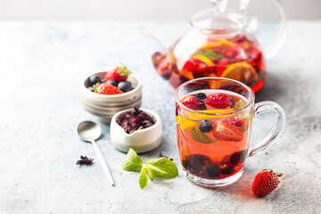 Fruit red tea with berries in glass cup on white background