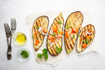 Grilled eggplant slices, garnished with fresh herbs, on white background, top view