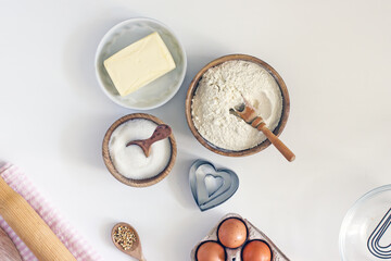 Ingredients for home baking cookies butter, sugar, eggs, flour, cookie cutters, rolling pin on a light background, top view. DIY homemade cookies background