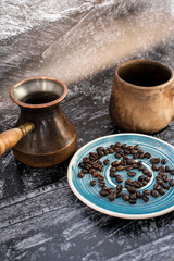 Fototapeta na wymiar Clay cup with cezve and coffee beans on a blue saucer. Coffee concept. Vertical photo