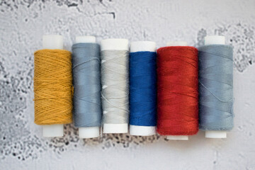Multicolored spools of thread on light background. Top view