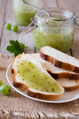Gooseberry jam on bread on wooden table