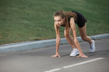 Young athlete on the treadmill in a low start position