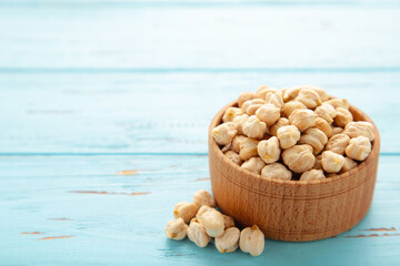 Uncooked dried chickpeas in wooden bowl on blue background. Vegan food concept