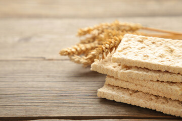 A slices of wheat crispbread with spikelets of wheat on grey wooden background.