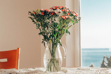 Flowers on the table by the window overlooking the sea