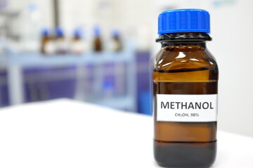Selective focus of methanol brown amber glass bottle inside a laboratory. Blurred background with copy space.	