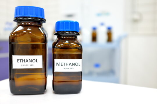 Selective focus of ethanol and methanol brown amber glass bottle inside a laboratory. Blurred background with copy space.	