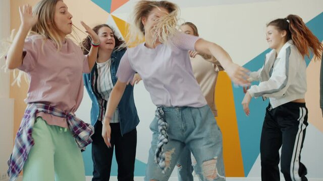 Creative young students are dancing indoors in hip-hop class having fun together, people are wearing trendy clothing and hat. Youth and activities concept.