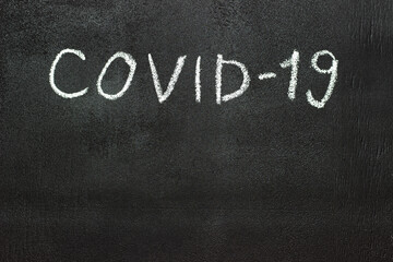 Obraz premium COVID-19 is written in white chalk on a chalk board.