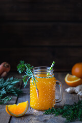 Healthy food. Carrots and carrot juice with orange ginger in a glass jar in a metal basket on a dark wooden background