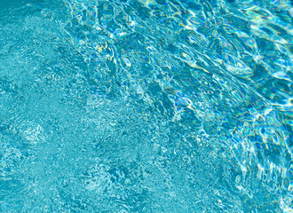 background with blue water with a play of light and ripples, water surface underwater, swimming pool surface, water background