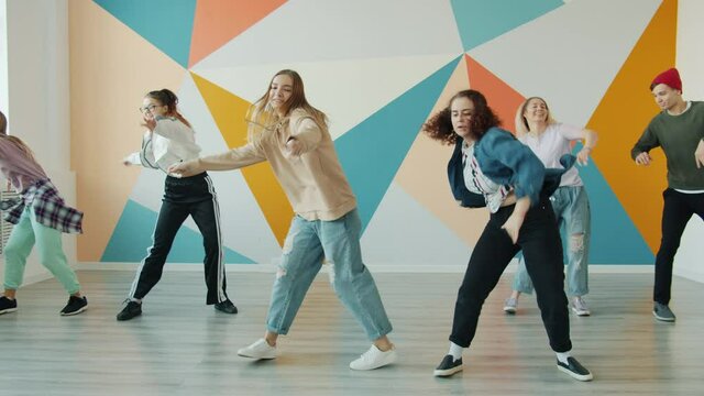 Active young people are dancing in modern hip-hop class moving arms and legs having fun together. Hobby, youth and contemporary art concept.