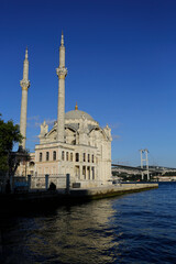 Fototapeta na wymiar The Ortakoy mosque, also known as Buyuk Mecidiye, is seen backgrounded by 15 July Martyrs bridge in Bosporus strait, Istanbul, Turkey.
