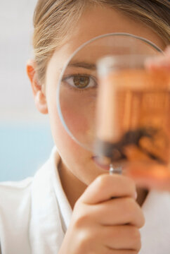 Close up curious junior school high girl with magnifying glass