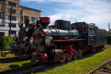Naklejka premium Stare lokomotywy parowe i samochody na zabytkowym dworcu kolejowym
