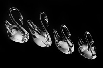 Crystal glass swans figurines on a dark background.
