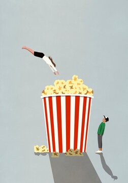 Woman diving into large movie theater popcorn tub
