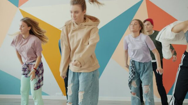 Young performers girls and guy are training practicing moves looking at teacher and repeating dance. Cultural education and youth culture concept.
