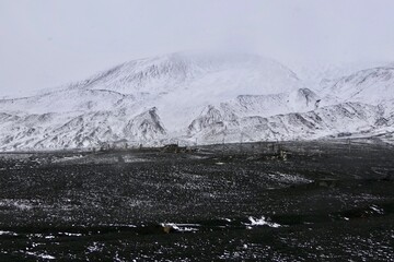 Antarctica, deception island, ruin in storm, snow on volcanic black stone
