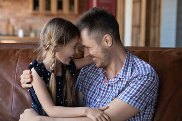 Overjoyed young Caucasian father and little daughter hug touch foreheads enjoy tender close moment...